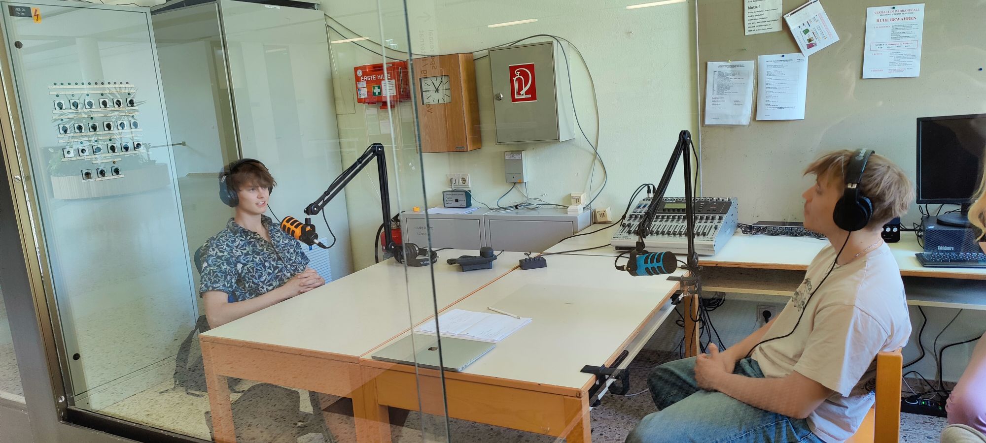 Schüler während Aufnahmen im Podcastraum sitzend vor Mikrofonen